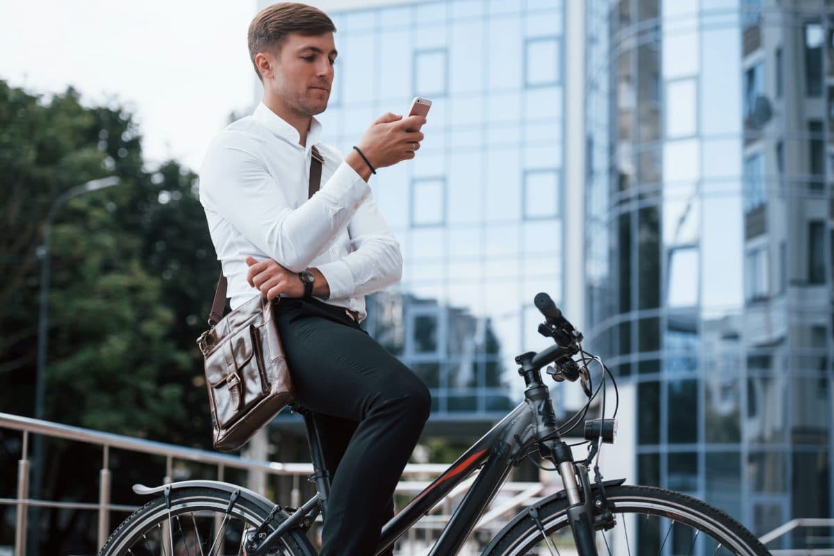 Reading news. Businessman in formal clothes with black bicycle is in the city